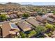 An aerial view of a desert neighborhood with tile-roofed homes, backyard patios, and mountain views in the distance at 10749 W Lariat Ln, Peoria, AZ 85383