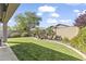 Serene backyard featuring lush green lawn, palm trees, flowering shrubs, and a rock waterfall feature at 10749 W Lariat Ln, Peoria, AZ 85383