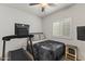 Cozy bedroom showcasing neutral tones, with a treadmill, television, ceiling fan, and window with shutters at 10749 W Lariat Ln, Peoria, AZ 85383