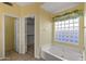 Bathroom featuring a garden tub with natural light from a glass block window, paired with an adjacent closet at 10936 N Ventana W Dr, Peoria, AZ 85373