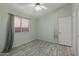 Bedroom featuring wood-look flooring, a window with blinds, and a door, offering a simple, clean aesthetic at 10936 N Ventana W Dr, Peoria, AZ 85373