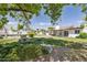 Expansive backyard featuring lush lawn, mature trees, stone benches and covered patio at 1452 E Gary St, Mesa, AZ 85203