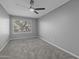 Neutral-toned bedroom featuring fresh gray paint, modern ceiling fan, new carpet, and natural light from the window at 15235 S 30Th St, Phoenix, AZ 85048