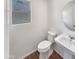 This powder room features a modern sink, round mirror, toilet, and wood-look vinyl flooring at 16236 W La Ventilla Way, Goodyear, AZ 85338