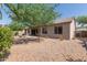 Backyard featuring gravel, trees, and exterior of home with covered patio at 1642 E Desert Ln, Phoenix, AZ 85042