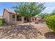 Rear view of home exterior and backyard, featuring gravel, trees, and a fire pit at 1642 E Desert Ln, Phoenix, AZ 85042