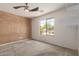 A bright carpeted bedroom with a ceiling fan and natural light coming in through a large window at 1642 E Desert Ln, Phoenix, AZ 85042