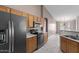 Functional kitchen with a black fridge, wood cabinets, and a view to living room with a breakfast bar at 1642 E Desert Ln, Phoenix, AZ 85042
