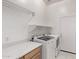Well-lit laundry room with modern washer, dryer, folding counter, shelving, and backyard access at 279 W Stirrup Ln, San Tan Valley, AZ 85143