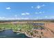This aerial view showcases a community lake, playgrounds and landscaped surroundings under a vibrant blue sky with fluffy clouds at 3010 E Fruitvale Ave, Gilbert, AZ 85297