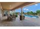 Outdoor patio with brick floor, stone pillars, dining table, pool, water slide, trampoline, and blue skies at 3010 E Fruitvale Ave, Gilbert, AZ 85297