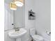 Powder room featuring a pedestal sink, toilet, stylish lighting and wall decor at 3010 E Fruitvale Ave, Gilbert, AZ 85297