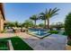 Backyard features a pool with palm trees, a spa, and a fire pit with ample seating under a clear blue sky at 30404 N 131St Dr, Peoria, AZ 85383