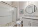 Clean and modern bathroom featuring a glass-enclosed shower with pebble floor, white cabinets, and a stylish round mirror at 30404 N 131St Dr, Peoria, AZ 85383