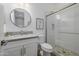 Modern bathroom featuring a glass-enclosed shower with pebble floor, white cabinets, and a stylish round mirror at 30404 N 131St Dr, Peoria, AZ 85383