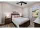 Comfortable bedroom with a wooden bed frame, side tables, ceiling fan, and bright natural light streaming through the window at 30404 N 131St Dr, Peoria, AZ 85383