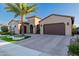Single Gathering home featuring a three car garage, brick driveway and desert landscaping with a palm tree at 30404 N 131St Dr, Peoria, AZ 85383