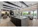 Modern kitchen featuring a granite island, stainless steel appliances, and open floor plan to dining and living rooms at 30404 N 131St Dr, Peoria, AZ 85383