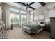 Bright main bedroom boasts large windows, wood floors, a ceiling fan, and stylish furnishings at 30404 N 131St Dr, Peoria, AZ 85383