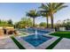 Luxury pool and patio area with dual palm trees, a cascading water feature, and travertine pavers at 30404 N 131St Dr, Peoria, AZ 85383