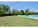 Relaxing backyard featuring a pool, lush green grass, mature trees, and ample privacy, perfect for outdoor entertaining at 325 W Loma Ln, Phoenix, AZ 85021