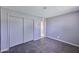 A bedroom with bare concrete flooring, gray walls, closet with sliding doors and a bathroom doorway at 325 W Loma Ln, Phoenix, AZ 85021