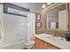 Well-lit bathroom featuring a tub-shower combo with modern fixtures and decorative mirror at 3338 E Lavey Ln, Phoenix, AZ 85032