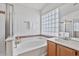 Bright bathroom featuring a soaking tub with glass block window, and a separate shower at 3338 E Lavey Ln, Phoenix, AZ 85032