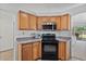 Modern kitchen with wooden cabinets, granite countertops, black appliances, and efficient layout at 3338 E Lavey Ln, Phoenix, AZ 85032