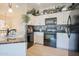 Well-lit kitchen featuring white cabinets, black appliances, granite countertops, and a tile backsplash at 34979 N 30Th Ave, Phoenix, AZ 85086