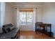 Cozy living room featuring hardwood floors, a futon, desk with chair, and a bright window at 34979 N 30Th Ave, Phoenix, AZ 85086