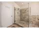Bathroom with a spacious glass shower stall tiled with decorative stone, tiled floor, and a door for additional storage at 37334 N 17Th Ave, Phoenix, AZ 85086