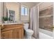Bright bathroom with a wood vanity, granite countertop, decorative mirror, and a shower-tub combination with decorative tile and curtain at 37334 N 17Th Ave, Phoenix, AZ 85086
