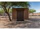 Outbuilding with an adobe exterior and dual doors, partially shaded by a mesquite tree at 37334 N 17Th Ave, Phoenix, AZ 85086