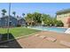 Backyard featuring a refreshing in-ground pool, lush green lawn, mature trees, and ample space for outdoor activities at 530 W Willetta St, Phoenix, AZ 85003