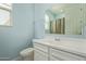 Well-lit bathroom featuring a white vanity, toilet, mirror, and a window, providing a clean and functional space at 7620 W Pioneer St, Phoenix, AZ 85043