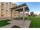 Outdoor lounge area featuring seating under a pergola, surrounded by green lawns and the building at 7970 E Camelback Rd # 101, Scottsdale, AZ 85251
