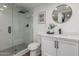 Modern bathroom featuring a glass shower, black fixtures, toilet, white vanity, decorative mirror, and artwork at 1174 E Belmont Ave, Phoenix, AZ 85020