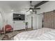 Bright main bedroom featuring a ceiling fan, large television, modern ensuite bathroom, and wooden closet door at 1174 E Belmont Ave, Phoenix, AZ 85020