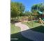 Spacious backyard featuring a curved walkway, artificial grass, trees, and a playset at 2018 W Marconi Ave, Phoenix, AZ 85023