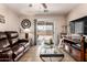 Cozy living room with tile floors, a leather sofa, glass table, and sliding glass door to the yard at 22543 W Cocopah St, Buckeye, AZ 85326