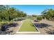 Bocce ball court surrounded by lush landscaping with a lake view offers recreational fun for residents at 23042 E Excelsior Ave, Queen Creek, AZ 85142