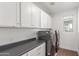 Laundry room with sleek, black appliances, white cabinets, and a neutral countertop offers modern convenience at 23042 E Excelsior Ave, Queen Creek, AZ 85142