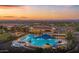 Aerial view showcasing a complex with a beautiful pool and luxurious amenities with a stunning colorful sunset backdrop at 26484 W Mohawk Ln, Buckeye, AZ 85396