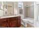Bright bathroom featuring a vanity with brown cabinets, a toilet, and a shower/tub combination at 26484 W Mohawk Ln, Buckeye, AZ 85396