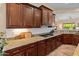 This kitchen features granite countertops, dark wood cabinets, tile flooring, and stainless steel appliances at 26484 W Mohawk Ln, Buckeye, AZ 85396