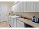 Well-equipped laundry room with a washer, dryer, white cabinets, and a countertop at 26484 W Mohawk Ln, Buckeye, AZ 85396