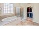 Elegant bathroom with a soaking tub, glass-enclosed shower, and access to a walk-in closet at 26484 W Mohawk Ln, Buckeye, AZ 85396
