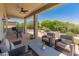 Comfortable covered patio with cushioned seating, ceiling fan, and views of the landscaped backyard at 26484 W Mohawk Ln, Buckeye, AZ 85396