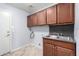 Spacious laundry room featuring tile floors, wooden cabinets, and a stainless steel sink at 43581 W Mccord Dr, Maricopa, AZ 85138